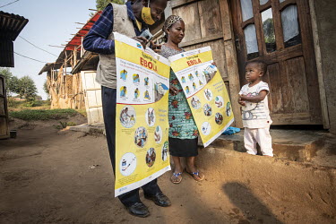 A child looks at community health workers conducting house-to-house outreach educating the local population on the need for vaccinations.  An Ebola outbreak was declared on 7th February in Butembo,...