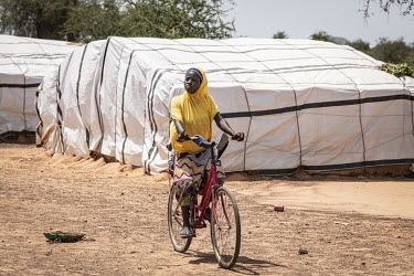 A woman rides a bicycle through an IDP camp outside Ouagadougou.  Once considered 'safe', Burkina Faso (meaning 'land of the upright man') is suffering from increasing instability as a result of attac...