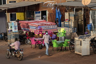 A man walks past a shop stall selling mattresses, furniture and various household appliances.