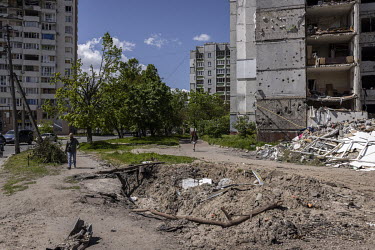 People walk past a series of destroyed apartment blocks in a residential area was a hit by a Russian warplane on the 3 March 2022, killing 47 civilians.