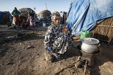 A Fulani woman and her child sit beside a cooking pot outside a shelter in an IDP camp.  Thousands of Fulani (semi-nomadic herders of the Sahel) have been displaced by fighting with the Dogon people a...