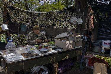 A Territorial Defence Forces soldier prepares food at a frontline position near the town of Barvinkove.