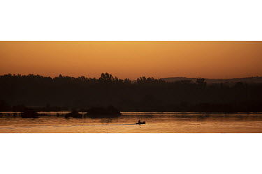 A lone man in a canoe (pirogue) on the Niger River.