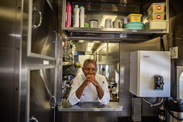 Assistant catering and logistics manager Vumile Ndamase looks through a hatch in the kitchen onboard the Phelophepa healthcare train. Vumile, who worked in a restaurant before joining the Phelophepa i...