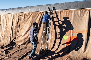 Workers install an awning on the side of the Phelophepa healthcare train as they prepare to receive patients ahead of a two week stay in the town of Thaba Nchu. The train has been providing primary he...