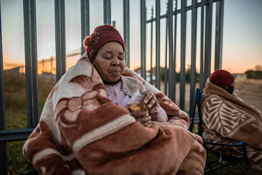 Doris MoKabi wraps herself in a thick blanket and snacks on popcorn as she settles in to sleep overnight outside the railway platform in Thaba Nchu, ahead of a visit to the Phelophepa healthcare train...