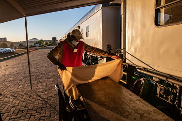 A worker lays down a cloth on a reception table at the start of the day beside the Phelophepa healthcare train. The train has been providing primary health services to remote and under-resourced areas...
