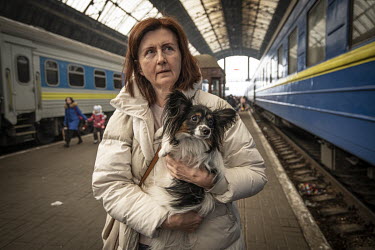 A woman fleeing the Russian invasion holds her pet dog in her arms at Lviv Central railway station