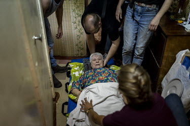 Volunteers from the UK and Ukraine, working with the NGO Vostok-SOS, help Zinaida (77), who is blind and struggled to walk, onto a fabric stretcher before lifting her down five flights of stairs durin...