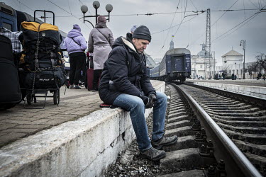 A man sits beside the tracks at Lviv Central railway station.