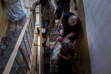Volunteers from the UK and Ukraine, working with the NGO Vostok-SOS, help Zinaida (77), who is blind and struggled to walk, carrying her down five flights of stairs during an evacuation mission in the...