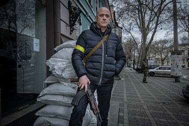 Gennady Trukhanov, the Mayor of Odesa, stands beside a pile of sandbags with an AK47 rifle.