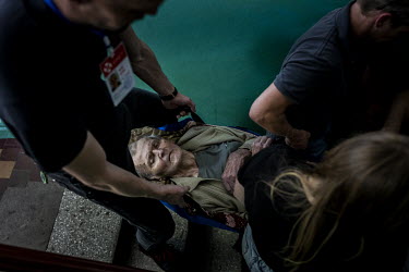 Volunteers from the UK and Ukraine, working with the NGO Vostok-SOS, prepare to carry Petro Boreyko (90) down five flights of stairs from his home during an evacuation mission in the city of Bakhmut....