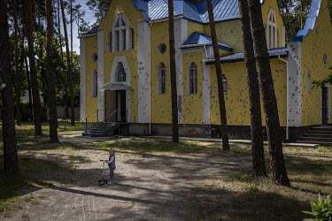 A young girl stands in front of a bullet riddled church in Irpin.