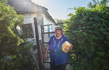 A woman with loaves of bread distributed by the Christian Church of Awakening She has decided not leave the village she says this is where she lives and where she wants to die. Pavlovka was occupied b...