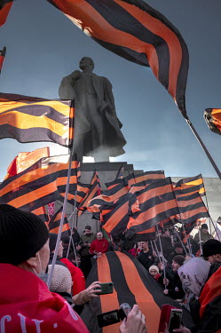 A crowd waving red and black St. George flags, which denote their support for Vladimir Putin, stand in front of a statue of Lenin at the Luzhniki stadium during a concert-rally dedicated to the eighth...