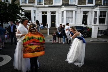 Liberty Samuel takes a picture of her mother Emma Samuel (L) and a child dresses as a burger at a Platinum Jubilee street party commemorating 70 years on the throne for HRH Queen Elizabeth II.