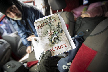 A refugee from Mauriupol holding the damaged passport of a companion who was injured by shellfire while walking her dog and has had part of her foot amputated. The group have now arrived in Zaporizhzh...