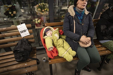 A woman and a child, refugees from Mauriupol, rest on a piece of garden furniture which still with the price tag attached, in a supermarket that is being used as a makeshift reception centre.