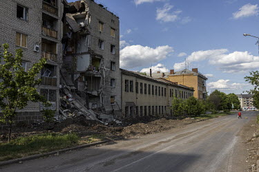 A woman walks her dog through deserted streets near a destroyed building that was hit by a Russian strike.