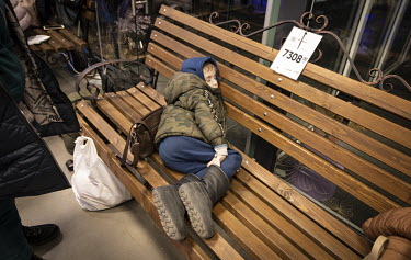 A boy sleeps on a piece of garden furniture which still with the price tag attached, in a supermarket that is being used as a makeshift reception centre to process refugees from Mauriupol.