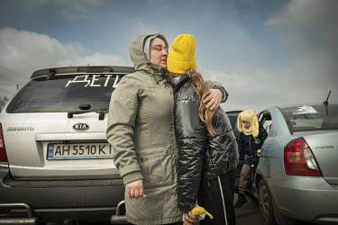 A woman embraces a child after arriving from Mauriupol at a makeshift reception centre in a Zaporizhzhia supermarket car park.