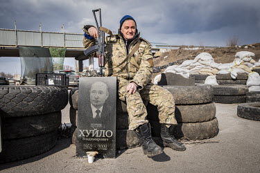 A soldier at a checkpoint in eastern Ukraine with an ironic tomb headstone featuring the image of Putin.