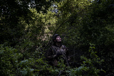 A Ukrainian artillery crew member looks out for surveillance drones after his crew fired on Russian positions near the city of Izium.