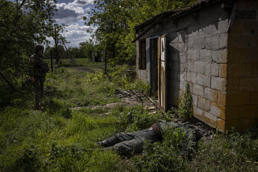 The body of a Russian soldier lies in the garden of a house in the recently recaptured village of Novopil.
