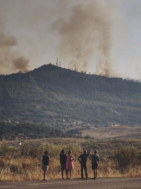 Locals watch from the roadside as smoke billows from the Casas de Miravete wildfire. The fire started on the 15 July 2022, threatening the Monfrague National Park and causing local villages to be evac...