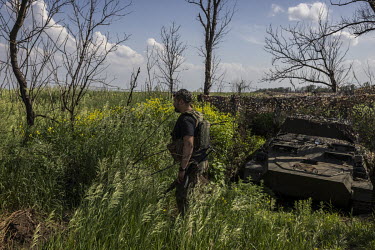 First Lieutenant, Semen Salatenko, walks past a camouflaged Ukrainian armoured fighting vehicle at a frontline position near Donetsk city.