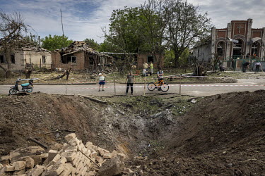 People peered into a large crater caused by a Russian missile that landed in a quiet residential area on the outskirts of Druzhkivka overnight. The strike caused widespread damage to civilian homes as...