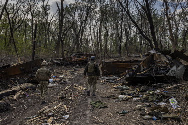 Ukrainian soldiers walk past destroyed Russian armoured vehicles in a forested area near the Seversky Donets river. Earlier in May 2022, Ukrainian forces had inflicted heavy losses on a Russian battal...