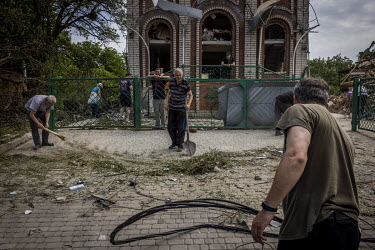 Local residents and parishioners clear up debris around a Baptist church in Druzhkivka, after a Russian missile strike hit a sleepy residential area on the outskirts of the city.
