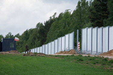 An armed border guard stands beside an unfinished section of the newly built border wall erected between Poland and Belarus.  In the autumn of 2021 there were clashes between Polish police and migrant...