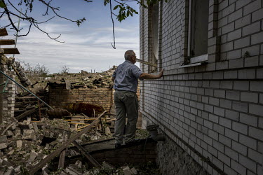 Vladimir Slobochikov tries to look inside his son's heavily destroyed house, after a Russian missile landed in the quiet residential area on the outskirts of Druzhkivka overnight. The strike caused wi...