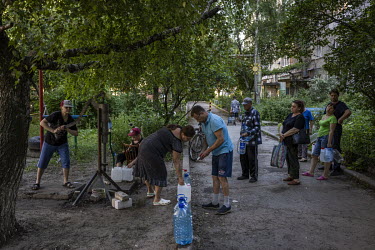People gather at a municipal water pump in Sloviansk to fill bottles and containers. Much of the city is without running water as Russian strikes have targeted water pumping stations. Gas and electric...