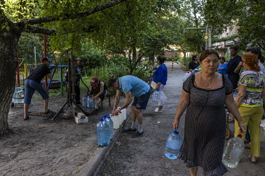People gather at a municipal water pump in Sloviansk to fill bottles and containers. Much of the city is without running water as Russian strikes have targeted water pumping stations. Gas and electric...