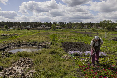 Zinaida Kostenko (67) tends to her flowers beside a large bomb crater full of water. Russian forces indiscriminately bombed Moshchun and much of Kyiv's northern suburbs as they pushed towards the capi...