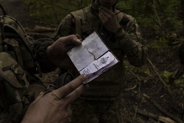 Ukrainian soldiers examine a booklet, denoting an award for military excellence to a Russian soldier, found near the scene of a failed Russian pontoon bridge crossing. Earlier in May 2022, Ukrainian f...