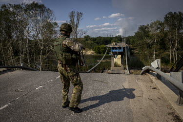 A member of the Ukrainian regional police force stands next to a bridge that connected the cities of Lysychansk and Sievierodonetsk and was destroyed by Russian forces the previous month.