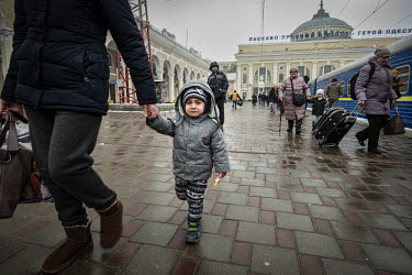 A young refugee child from Mykolayiv cries as they walk with an adult along a platform of Odessa's railway station prior to boarding a Lviv bound train.