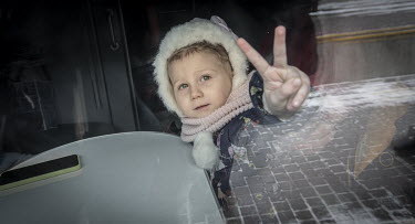 A child refugee from Mykolayiv gives a V-for-victory sign through the window of a Lviv bound train about to depart from Odessa's railway station.