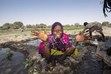 A woman washes her face after working in vegetable plots around which villagers are planting seeds of various trees species (acacia, desert date, guava, citron and mango trees) that they hope will sto...