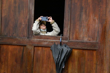 A sightseer taking a picture with a mobile phone inside the main courtyard of a restored ancient villa. Beigan is famed for it's deserted villages that have fallen in to disrepair as the island's yout...