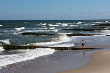 A woman walking between groynes on a beach at Zelenogradsk, one of the main resorts of the Kaliningrad region on the Baltic Sea. Durung the COVID-19 pandemic the exclave's borders were closed to inter...