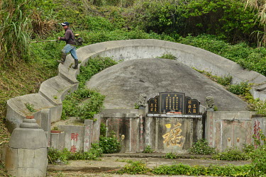 A workman trimming back the undergrowth around a grave in Tien Ao village, a once thriving settlement that went into decline after the standing-down of many of the ROC forces based in Matsu at the end...
