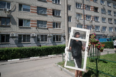 A man carries a window from a residential building, at the intersection of Popov and Mayakovsky streets, that had its windows blown out during an explosion on the night of 3 July 2022 which the Russia...
