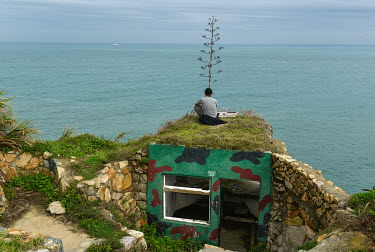 A man sits on a disused military bunker facing China, in Dapu village on Dongju islet, an increasingly popular location for Taiwanese domestic tourists. Frontline Dongju is part of the Matsu archipela...