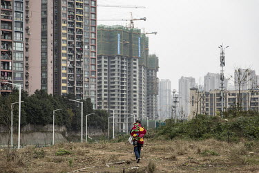 A man carrying a child on his back walks on a hill overlooking an jumble of elevated highways on the outskirts of Chongqing. China's largest municipality by population and land area, Chongqing is cent...